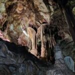 Stalactites and stalagmites in a cave under colored lighting