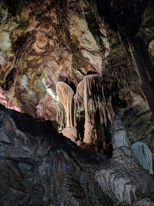 Stalactites and stalagmites in a cave under colored lighting